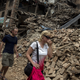 Tourists walk past collapsed houses in Bhaktapur, Nepal.